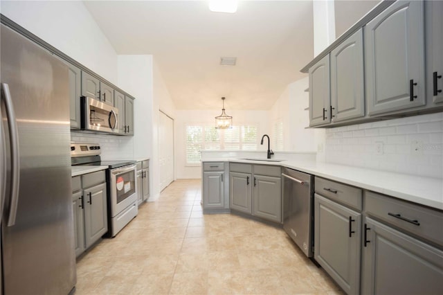 kitchen with vaulted ceiling, gray cabinetry, appliances with stainless steel finishes, and a sink