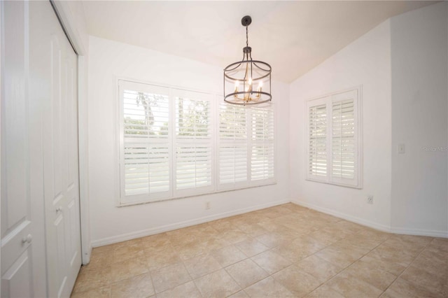 spare room with baseboards, plenty of natural light, lofted ceiling, and a chandelier