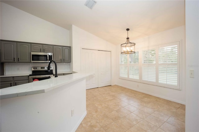 kitchen featuring vaulted ceiling, light countertops, appliances with stainless steel finishes, and gray cabinetry