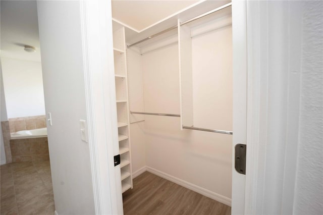 walk in closet with wood finished floors