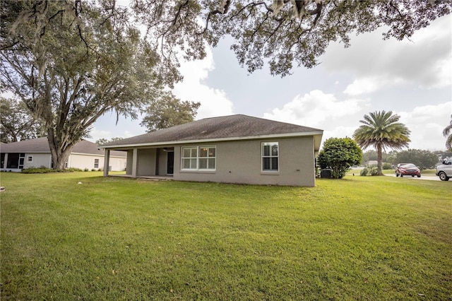 rear view of house with stucco siding and a lawn