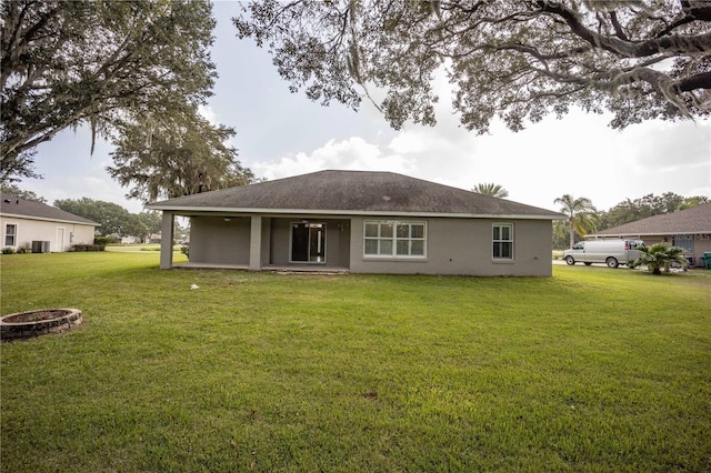 back of property featuring a lawn, cooling unit, an outdoor fire pit, and stucco siding