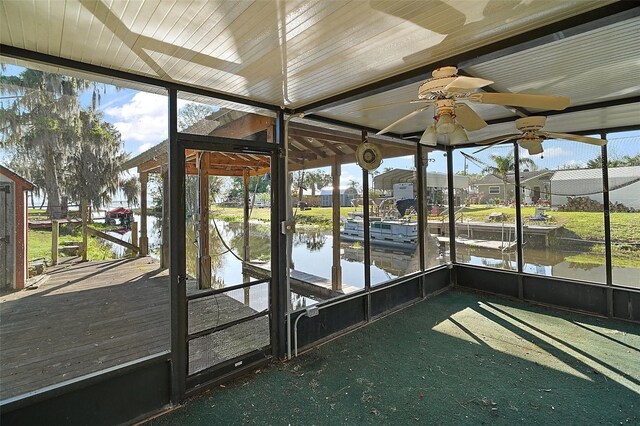 unfurnished sunroom featuring ceiling fan and a water view