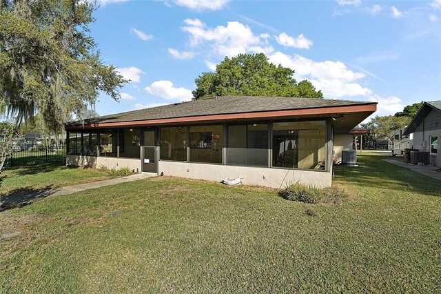 rear view of property featuring central air condition unit, fence, a yard, and a sunroom