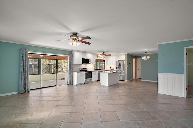 kitchen with open floor plan, white cabinetry, stainless steel appliances, light tile patterned flooring, and crown molding