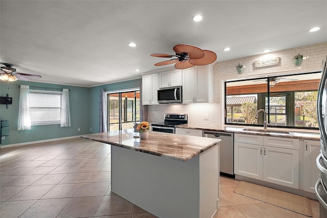 kitchen with a sink, backsplash, appliances with stainless steel finishes, and a center island