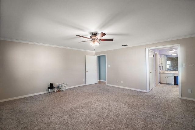 carpeted spare room with visible vents, baseboards, ornamental molding, a ceiling fan, and a sink