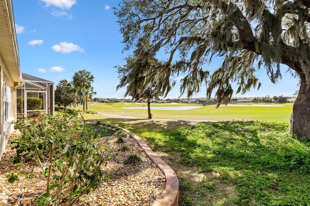 view of yard with a lanai and golf course view