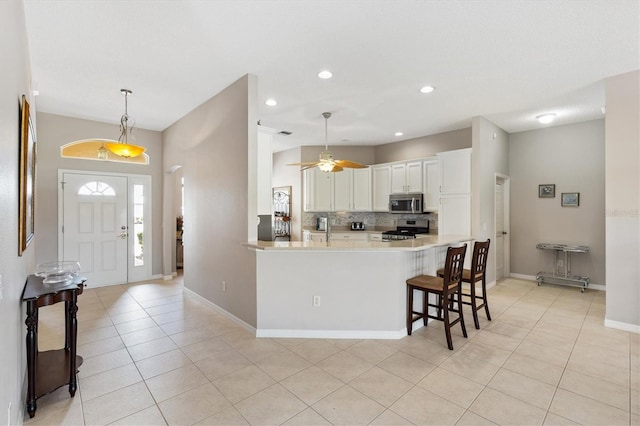 kitchen with light countertops, appliances with stainless steel finishes, pendant lighting, white cabinetry, and tasteful backsplash