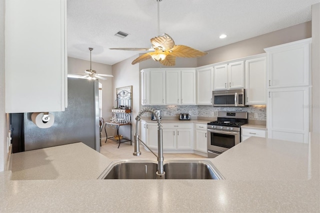 kitchen featuring a sink, stainless steel appliances, backsplash, and a ceiling fan