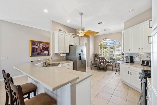 kitchen featuring visible vents, appliances with stainless steel finishes, a peninsula, a ceiling fan, and a sink