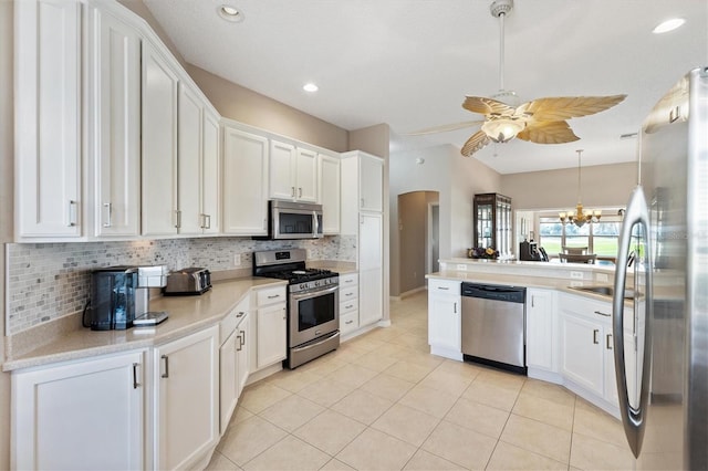 kitchen featuring tasteful backsplash, light countertops, appliances with stainless steel finishes, arched walkways, and white cabinetry