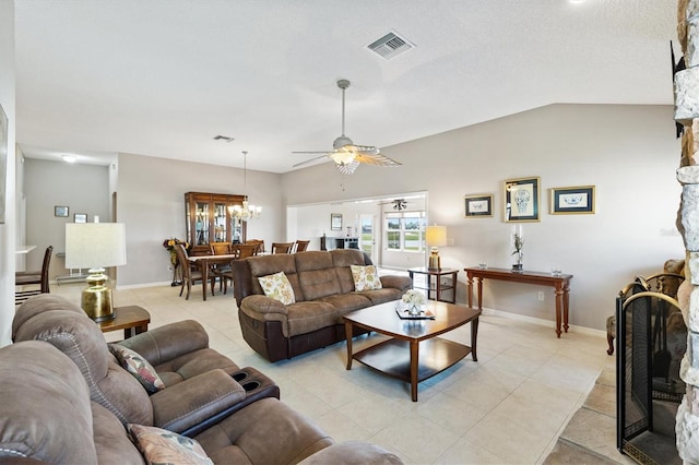 living area with visible vents, lofted ceiling, light tile patterned floors, a stone fireplace, and ceiling fan with notable chandelier