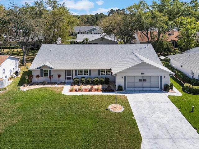 ranch-style home featuring an attached garage, concrete driveway, a front yard, and a shingled roof