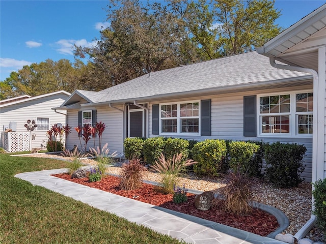 ranch-style house with a shingled roof and a front lawn