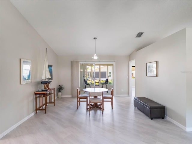 dining room featuring visible vents, light wood-type flooring, baseboards, and vaulted ceiling