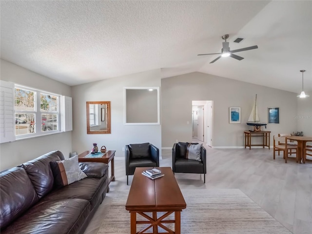 living room with light wood-type flooring, lofted ceiling, a textured ceiling, and visible vents