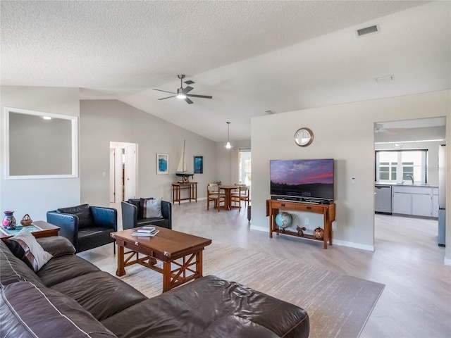 living area featuring visible vents, a textured ceiling, a ceiling fan, and lofted ceiling