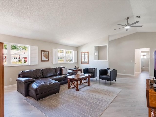 living area with a wealth of natural light, visible vents, light wood-style flooring, and lofted ceiling