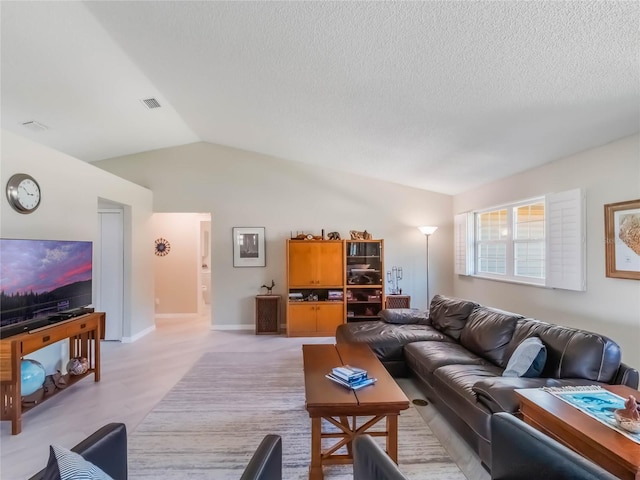 living area featuring baseboards, a textured ceiling, and vaulted ceiling