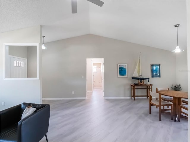 interior space featuring lofted ceiling, baseboards, light wood-type flooring, and ceiling fan