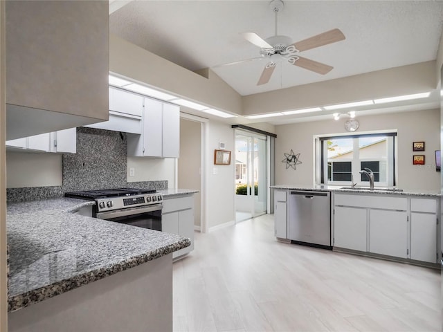 kitchen with light stone counters, decorative backsplash, appliances with stainless steel finishes, white cabinetry, and a sink