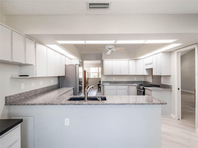 kitchen featuring visible vents, ceiling fan, a peninsula, stainless steel appliances, and a sink