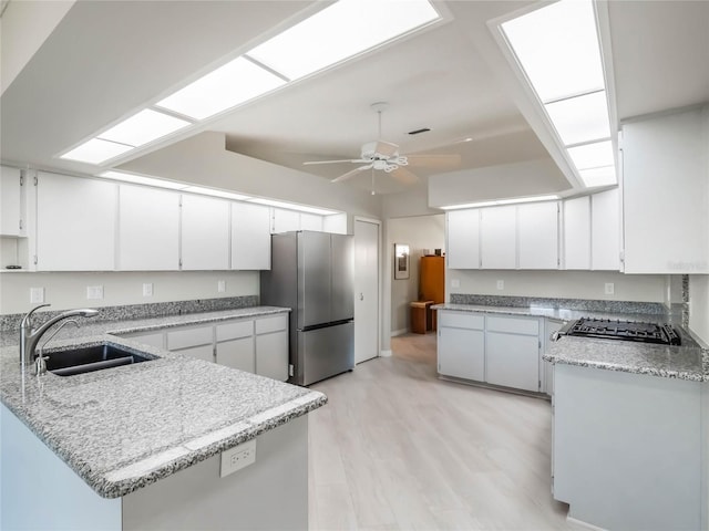 kitchen with freestanding refrigerator, light wood-style floors, white cabinetry, a ceiling fan, and a sink