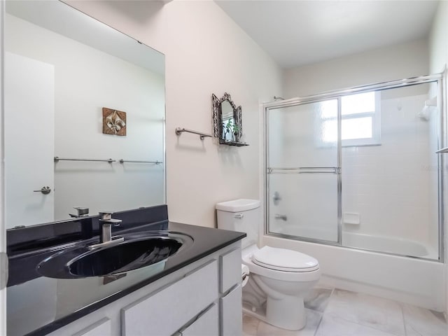 full bath with toilet, vanity, and shower / bath combination with glass door