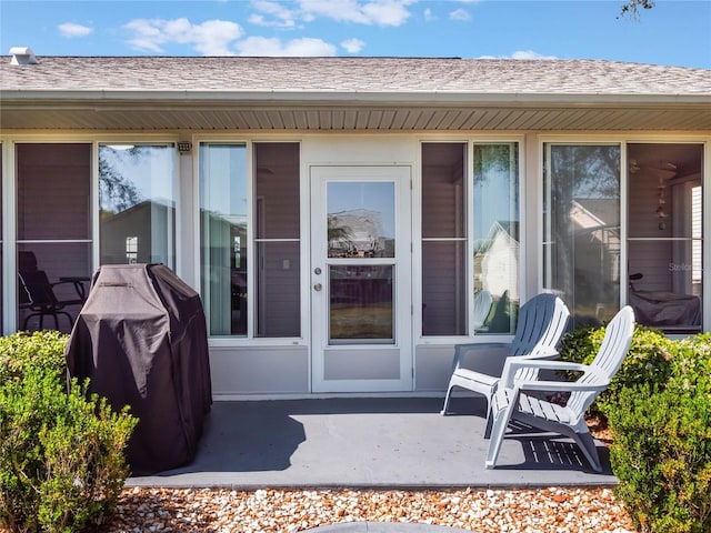 doorway to property with a patio and a shingled roof