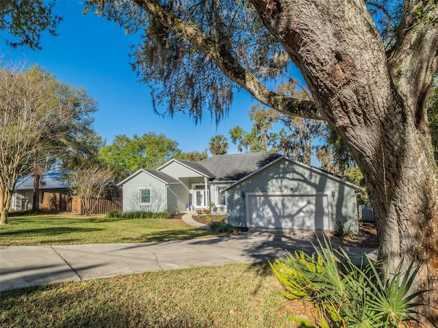 ranch-style home with a front lawn, an attached garage, fence, and driveway