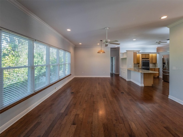 unfurnished living room with ornamental molding, dark wood-type flooring, ceiling fan, and a sink