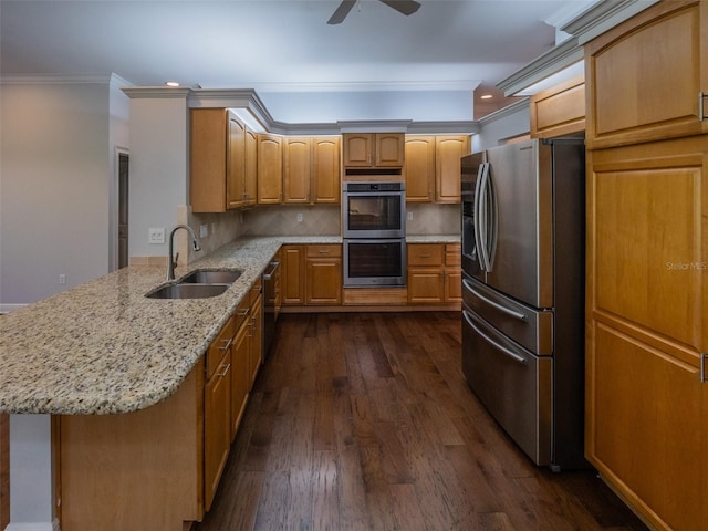 kitchen featuring dark wood finished floors, ornamental molding, a peninsula, stainless steel appliances, and a sink