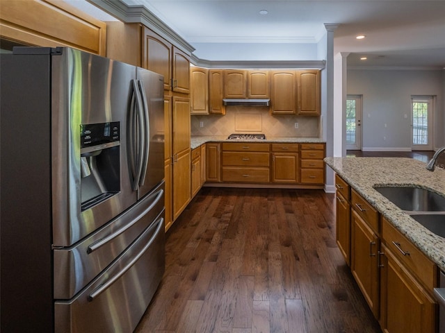 kitchen with dark wood-type flooring, light stone countertops, ornamental molding, stainless steel appliances, and a sink