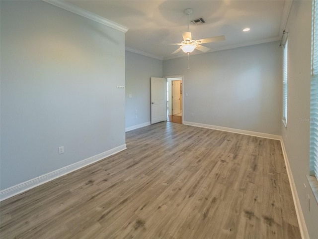 spare room featuring wood finished floors, baseboards, visible vents, ceiling fan, and crown molding