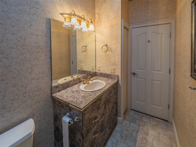 half bath with vanity, toilet, and baseboards