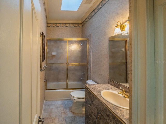 bathroom featuring vanity, a skylight, bath / shower combo with glass door, crown molding, and toilet