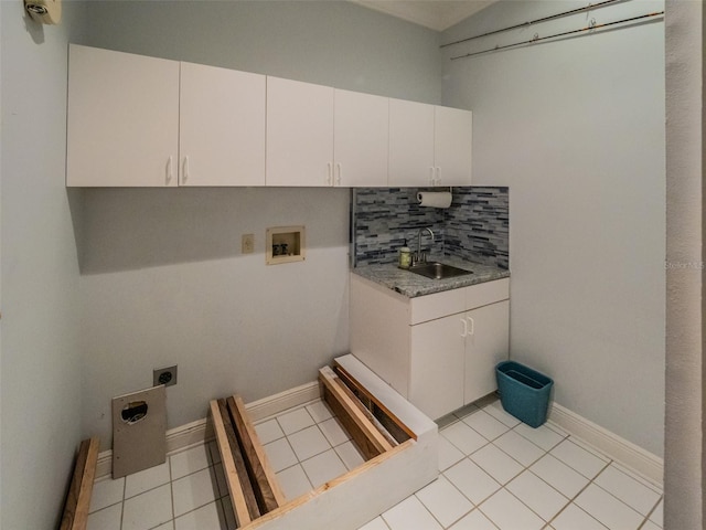 washroom featuring electric dryer hookup, washer hookup, a sink, cabinet space, and light tile patterned floors