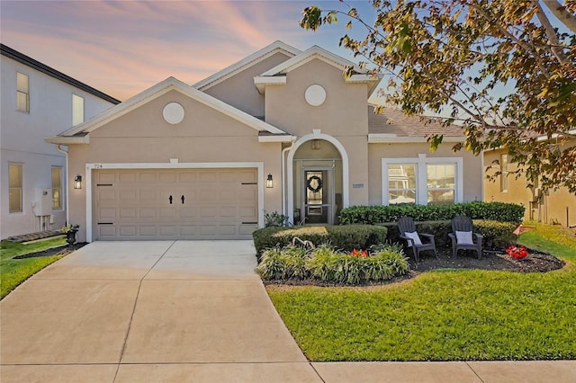 view of front facade with stucco siding, a front yard, a garage, and driveway