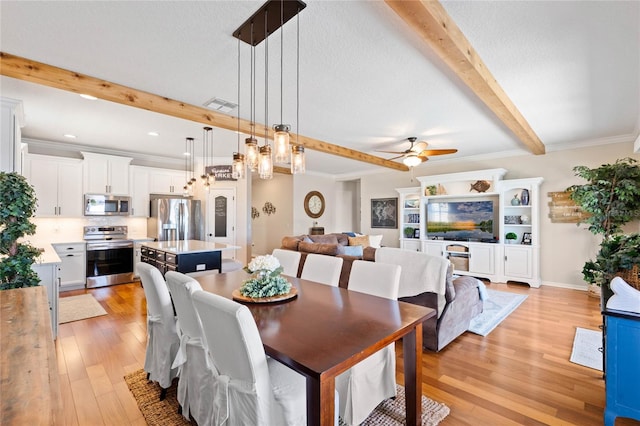 dining space featuring visible vents, crown molding, beamed ceiling, light wood-type flooring, and a ceiling fan