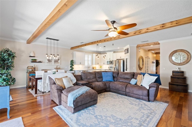 living area with ceiling fan, baseboards, light wood-type flooring, ornamental molding, and beam ceiling