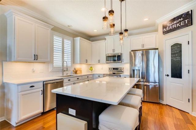 kitchen with a kitchen island, white cabinets, stainless steel appliances, and a sink