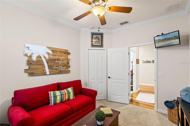 living area with baseboards, light colored carpet, visible vents, and ornamental molding