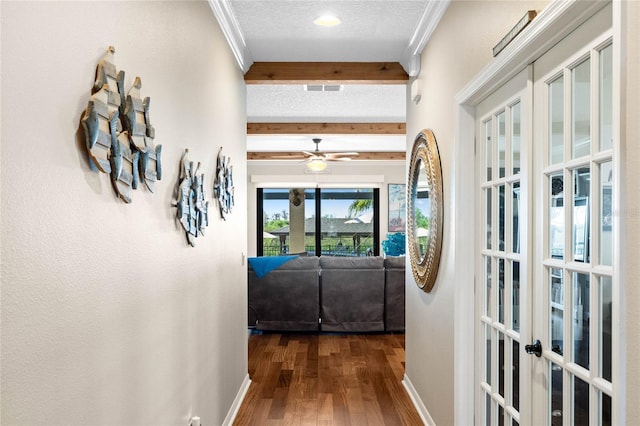 corridor with baseboards, ornamental molding, beam ceiling, a textured ceiling, and dark wood-style flooring