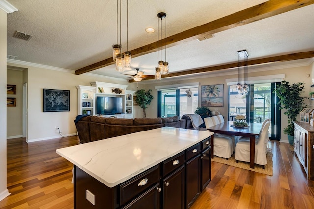 kitchen featuring visible vents, beamed ceiling, a textured ceiling, wood finished floors, and hanging light fixtures