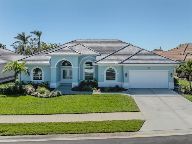 view of front of house with stucco siding, french doors, concrete driveway, a front yard, and a garage