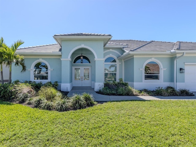 mediterranean / spanish home featuring a front yard, french doors, a tile roof, and stucco siding