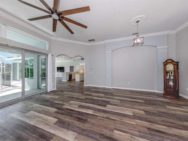 spare room featuring arched walkways, wood finished floors, baseboards, and ornamental molding