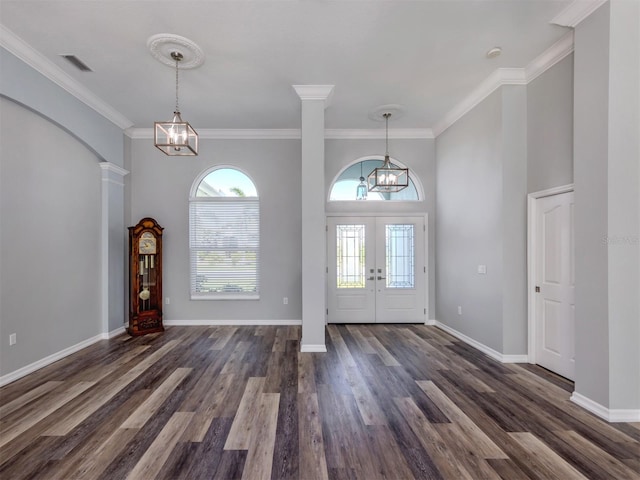 entrance foyer featuring dark wood-type flooring, french doors, arched walkways, a notable chandelier, and ornate columns