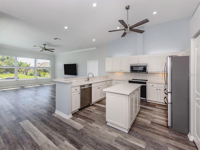 kitchen featuring a sink, tasteful backsplash, open floor plan, white cabinetry, and stainless steel appliances